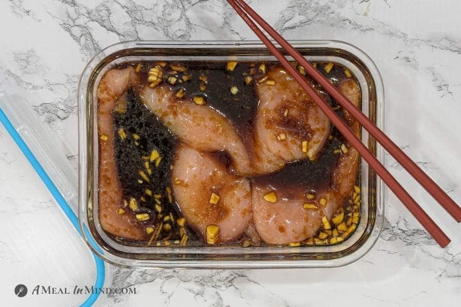 chicken breasts marinating in teriyaki sauce in glass dish