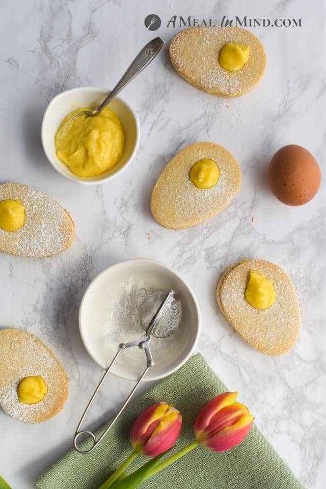 egg-shaped cookies with yellow lemon curd filling on a light background